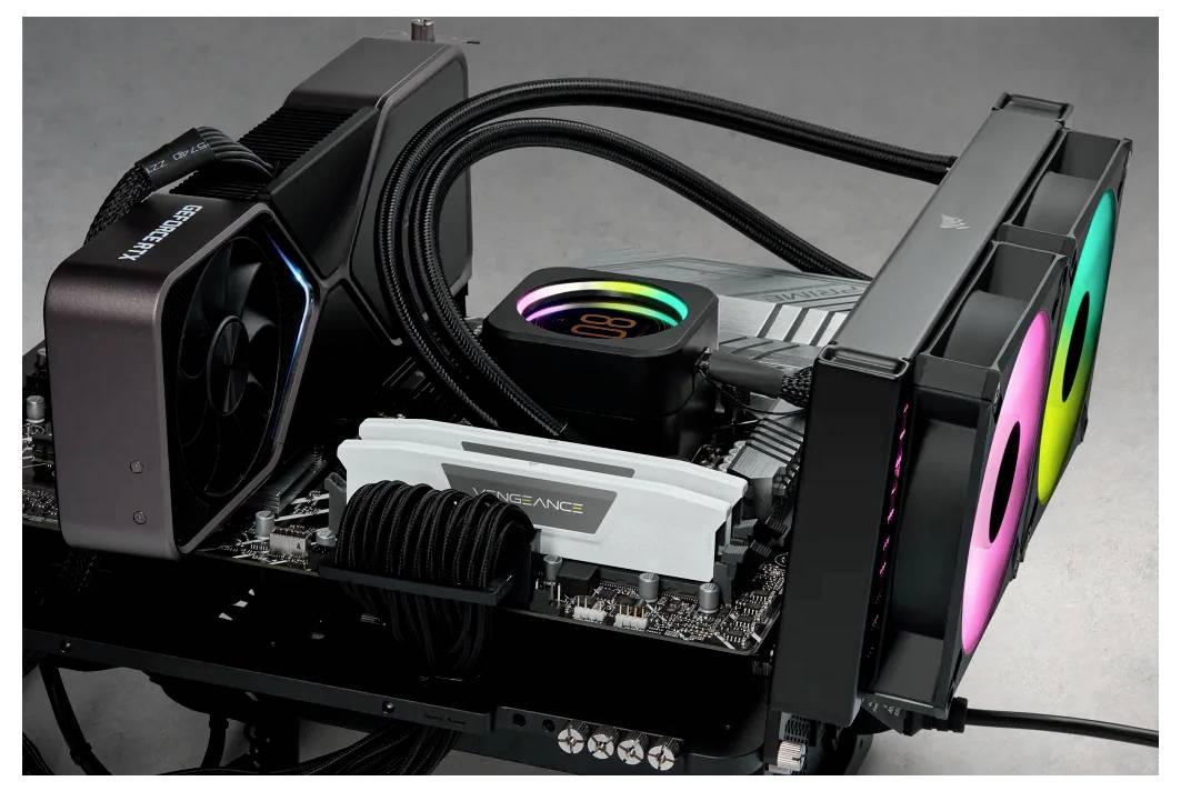 Ein offener Computer zeigt eine Grafikkarte, einen Kühlkörper mit RGB-Beleuchtung, einen RAM-Riegel und drei Lüfter mit farbigen LEDs.