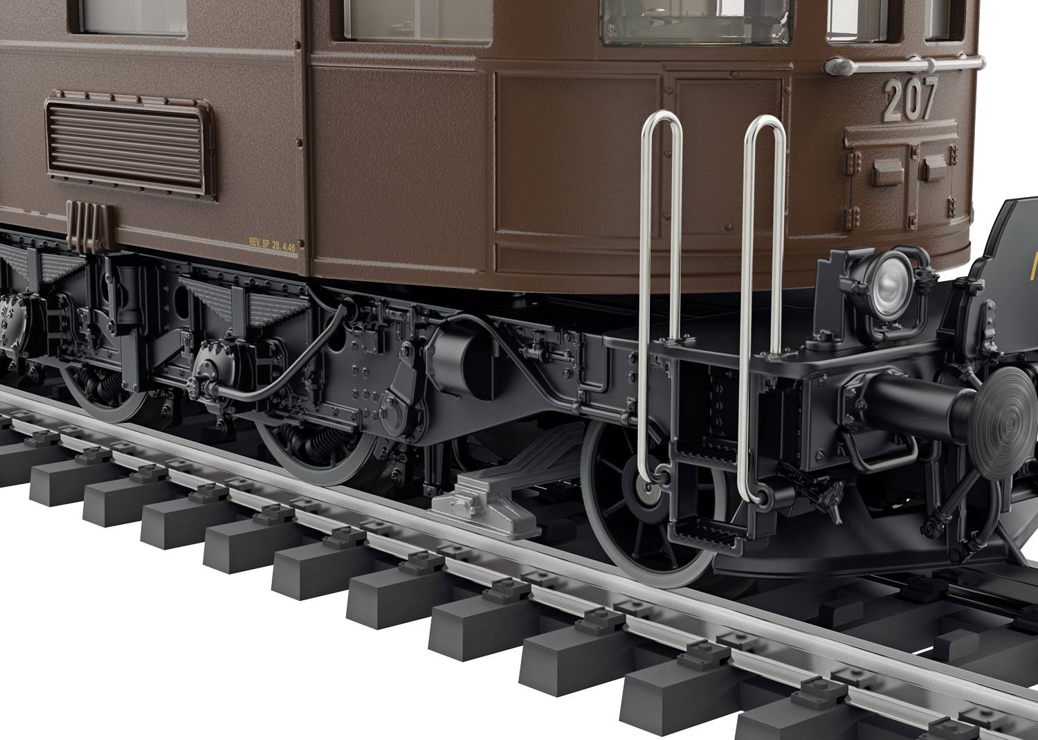 Nahaufnahme eines braunen Zugwagens auf Schienen, Fokus auf Fahrwerk und Details wie Leitungen und Puffer.