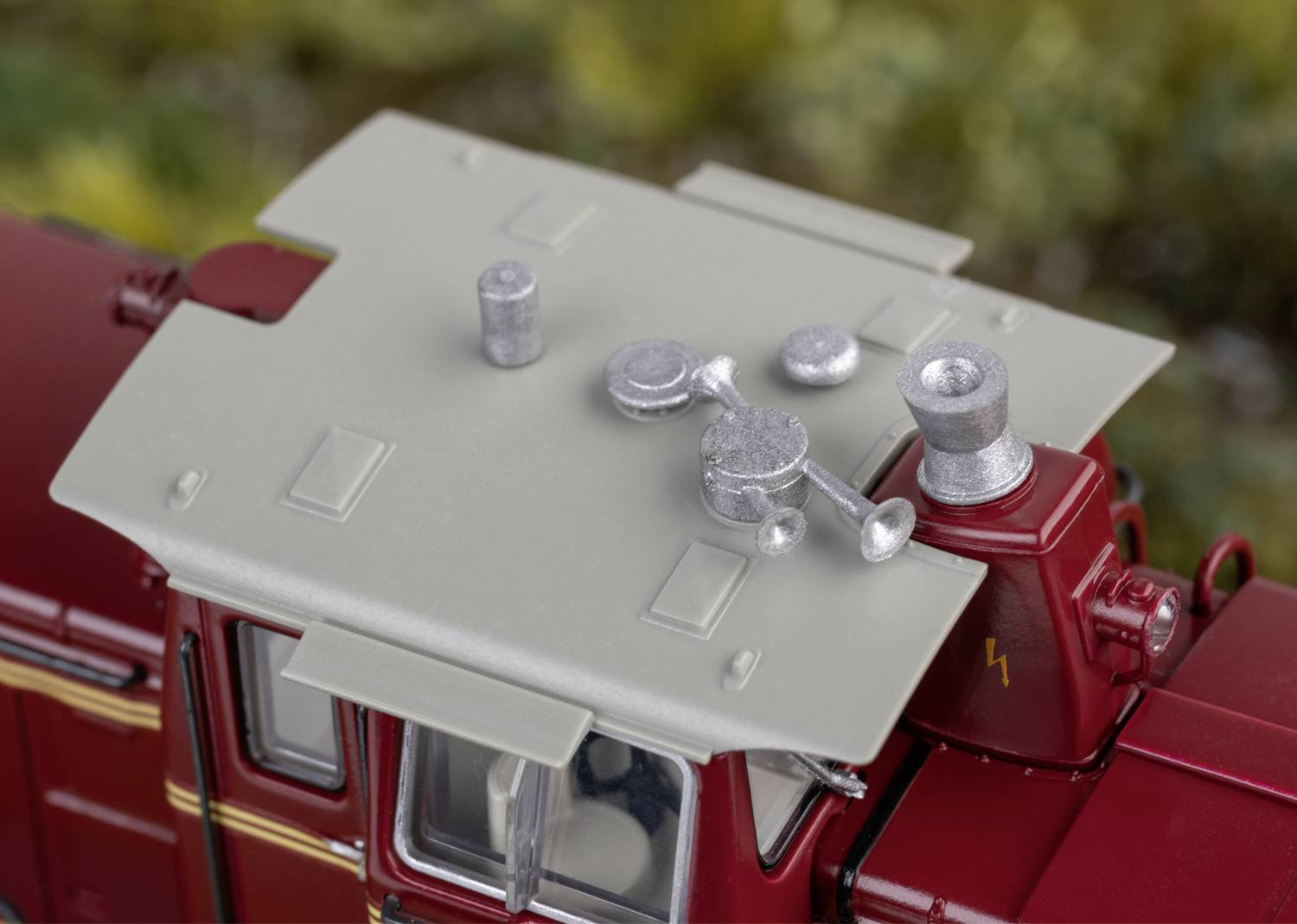 Nahaufnahme einer Miniatureisenbahn-Lokomotive. Detaillierte Ansicht des Dachs mit silbernen Bauteilen auf rotem Korpus. Hintergrund unscharf.