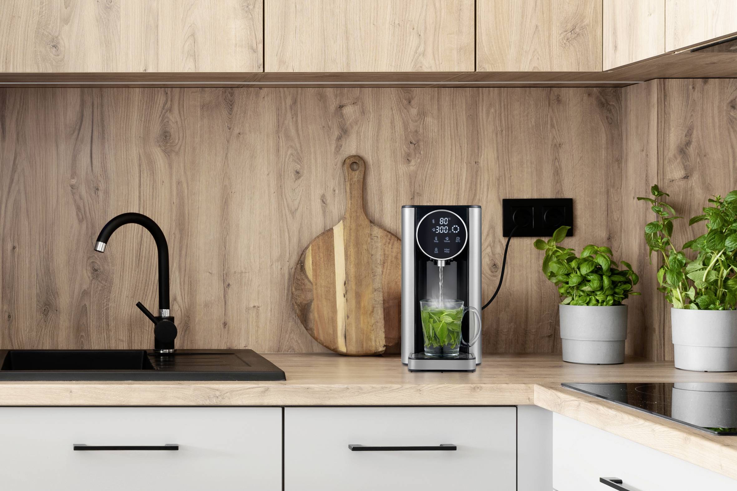 Küchenzeile mit einem Wassersprudler auf der Arbeitsplatte, daneben Basilikum in Töpfen, Holzschneidebrett an der Holzrückwand.