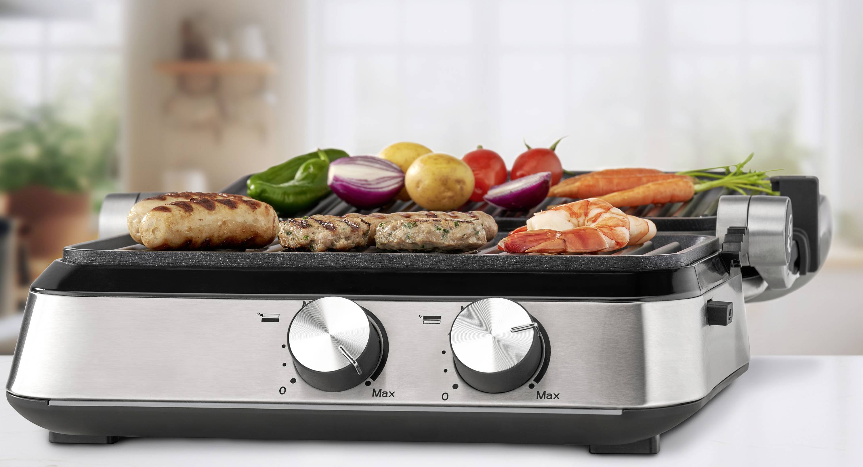 Ein moderner Tischgrill mit verschiedenen Lebensmitteln wie Würstchen, Gemüse und Garnelen, die im Hintergrund auf einer Küchenarbeitsplatte gegrillt werden.