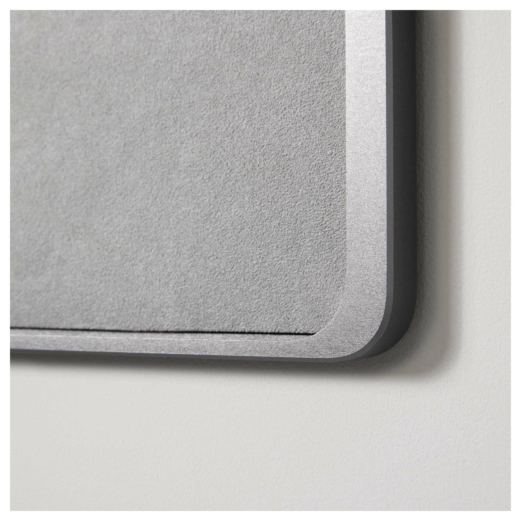 Nahaufnahme einer grauen Pinnwand mit abgerundeten Ecken, an der Wand montiert. Oberfläche aus Filzmaterial.
