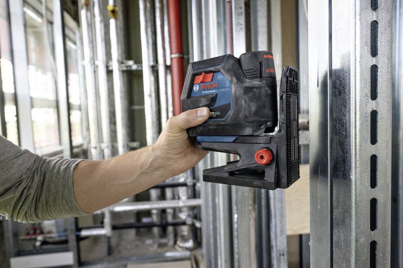 Eine Person benutzt ein Bosch Elektrogerät an einem Metallrahmen in einer Baustelle, um genaue Messungen durchzuführen.