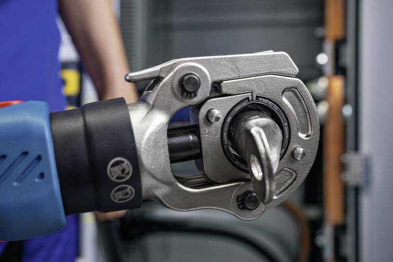 Nahaufnahme eines hydraulischen Rettungsgeräts, das an einem Metallrohr arbeitet, möglicherweise zur Rettung oder technischen Hilfeleistung.