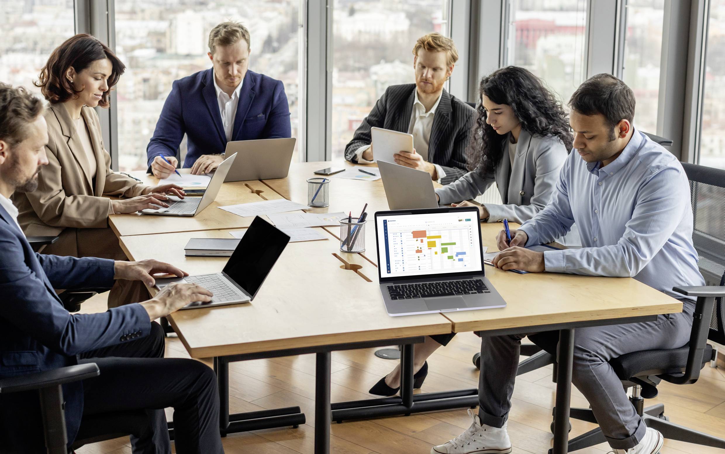 Personengruppe in einem modernen Büro bei einer Besprechung. Sie arbeiten an Laptops, diskutieren Dokumente und analysieren Diagramme.