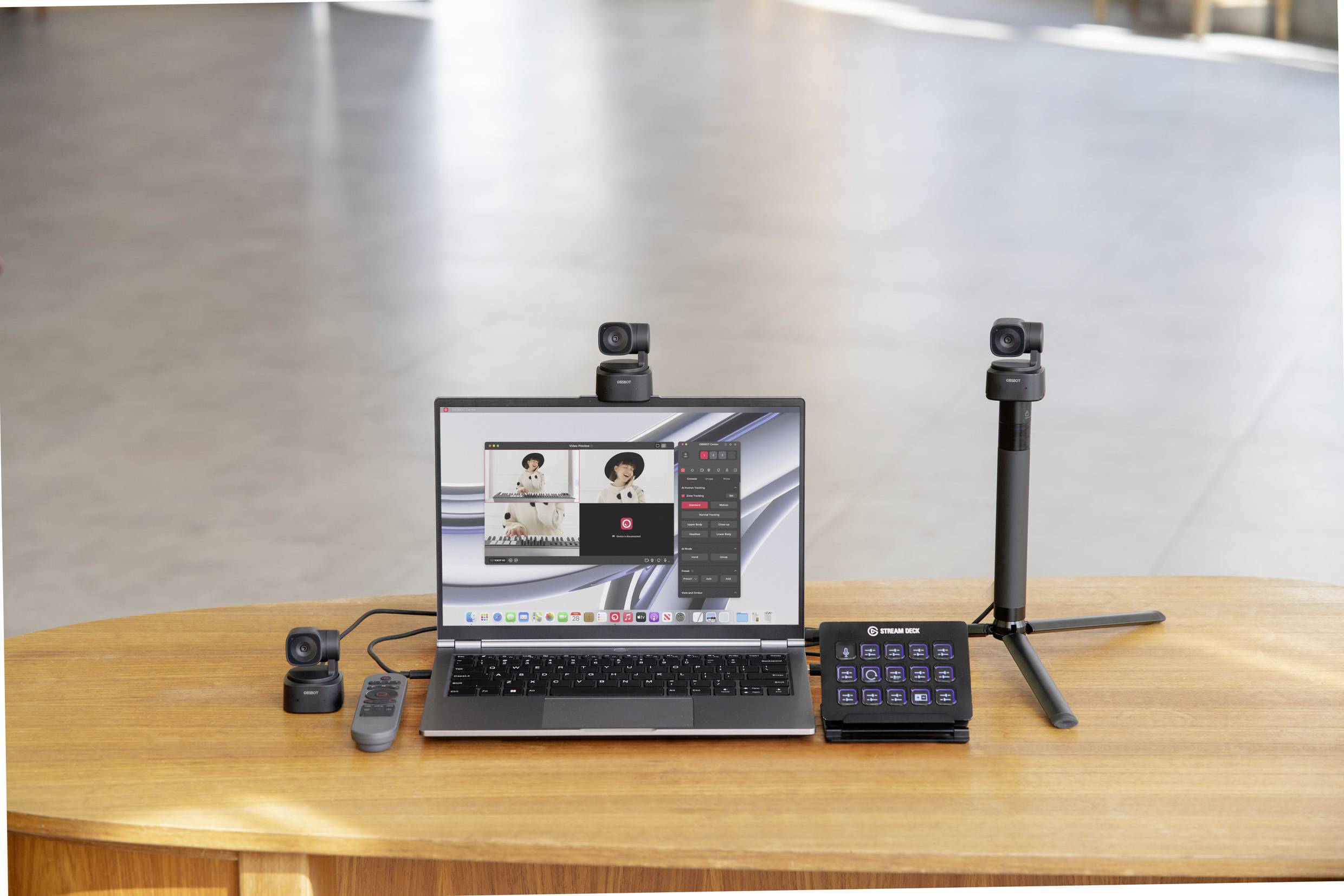 Ein Laptop auf einem Tisch zeigt ein Videokonferenz-Softwarefenster mit mehreren Teilnehmern. Daneben befinden sich Kameras und ein Fernbedienungsgerät.