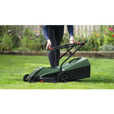 Eine Person mäht den Rasen mit einem grünen Elektrorasenmäher in einem Garten. Bunte Blumen sind im Hintergrund sichtbar.