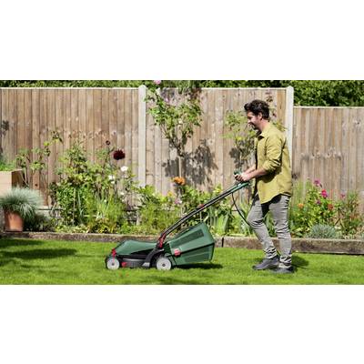 Eine Person mäht im Garten mit einem grünen Rasenmäher. Im Hintergrund sind verschiedene Blumen zu sehen.