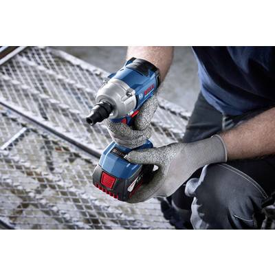 Eine Person hält einen blauen, kabellosen Akkuschrauber auf einem Metallgitterboden. Sie trägt graue, gepolsterte Handschuhe.
