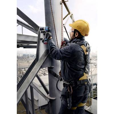 Ein Arbeiter in Schutzkleidung und Helm befestigt mit einem Schraubendreher Balken an einer Metallkonstruktion auf einer Baustelle.