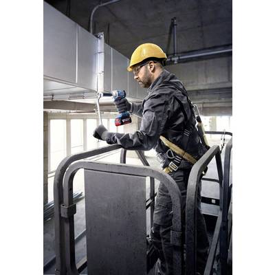 Ein Arbeiter in Sicherheitskleidung und Helm steht auf einer Hebebühne und arbeitet mit einem Bohrschrauber an einer Klimaanlage.