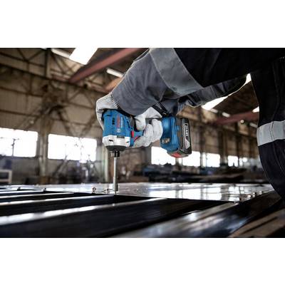 Eine Person hält und verwendet einen Akku-Bohrschrauber, um Metallplatten in einer Fabrikhalle zu befestigen.