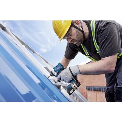Ein Bauarbeiter mit Helm und Sicherheitsweste arbeitet mit einem Elektrowerkzeug an einem blauen Metalldach unter freiem Himmel.