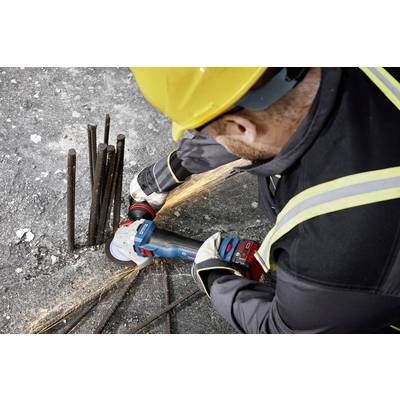 Ein Arbeiter mit gelbem Schutzhelm schneidet auf einer Baustelle Stahlstäbe mit einem Winkelschleifer, Funken fliegen herum.