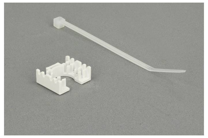 Ein weißes Kabelbinder-Set auf grauem Hintergrund, bestehend aus einem langen Kabelbinder und einem gebogenen Kunststoffhalter.