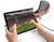 Eine Person hält ein Tablet, auf dem ein Fußballspiel mit einem Freistoß zu sehen ist. Das Tablet ist über ein Kabel verbunden.
