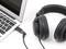 Laptop mit angeschlossenen Over-Ear-Kopfhörern, die seitlich auf einer Tischplatte liegen.