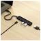 'Ein schwarzer USB-Hub mit zwei eingesteckten USB-Sticks ist an einen Laptop angeschlossen, der auf einem Holztisch steht.'
