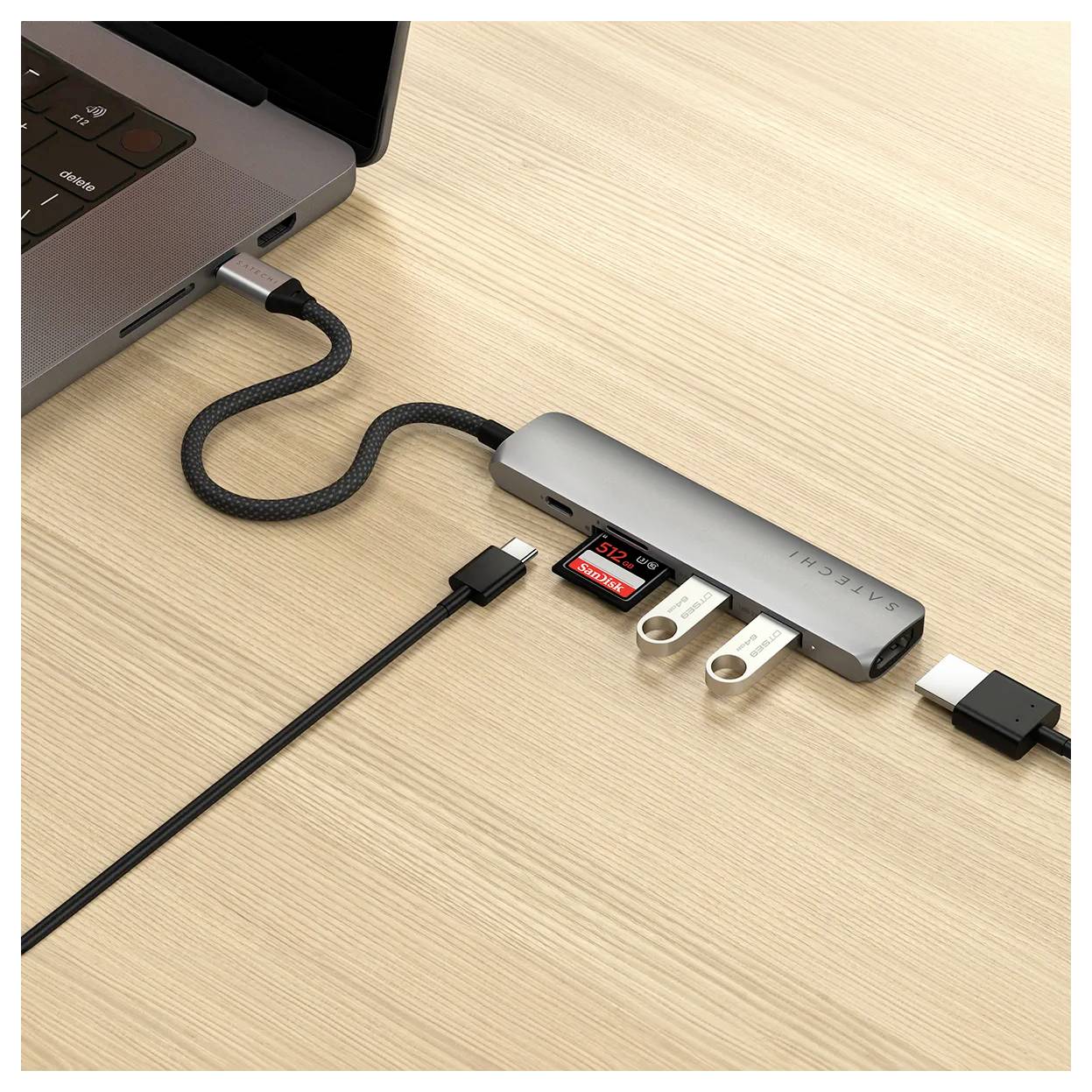 Ein Laptop ist über ein USB-C-Hub mit mehreren Anschlüssen verbunden. Das Hub hat einen USB-Stick und eine SD-Karte eingesteckt.