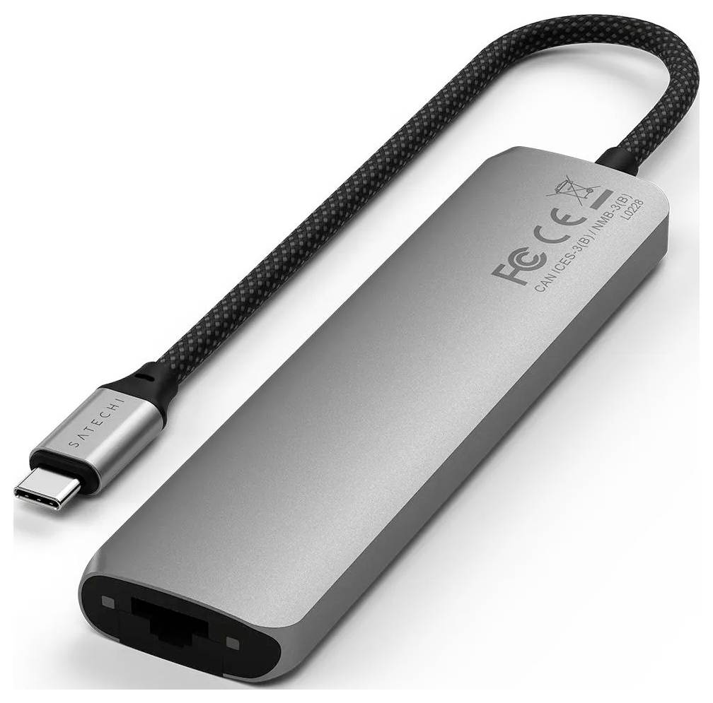 Ein silberner USB-C-Adapter mit mehreren Anschlüssen, darunter ein Ethernet-Anschluss, markiert mit CE- und FCC-Zeichen.