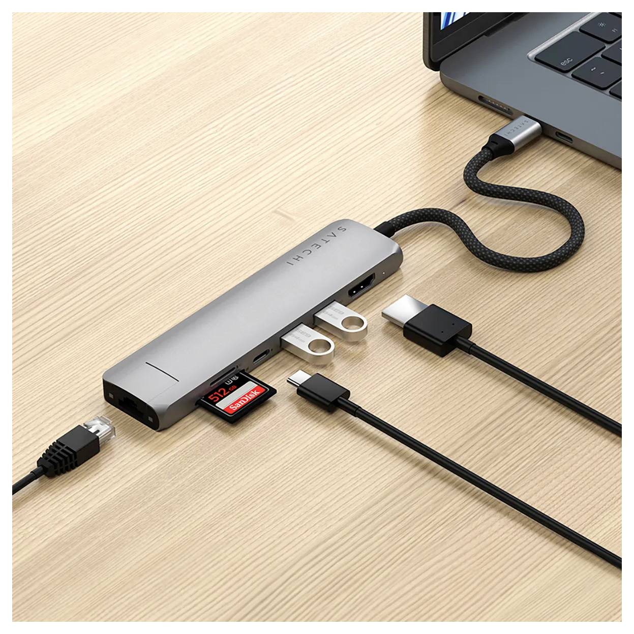 Ein USB-C-Hub ist an einen Laptop angeschlossen. Mehrere Kabel und ein SD-Karte sind eingesteckt. Er ermöglicht den Anschluss zusätzlicher Geräte.