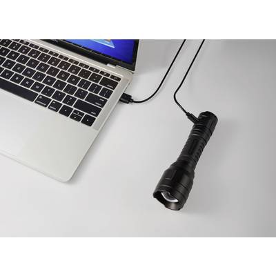 Ein Laptop verbunden mit einer Taschenlampe über ein USB-Kabel auf einem Tisch.