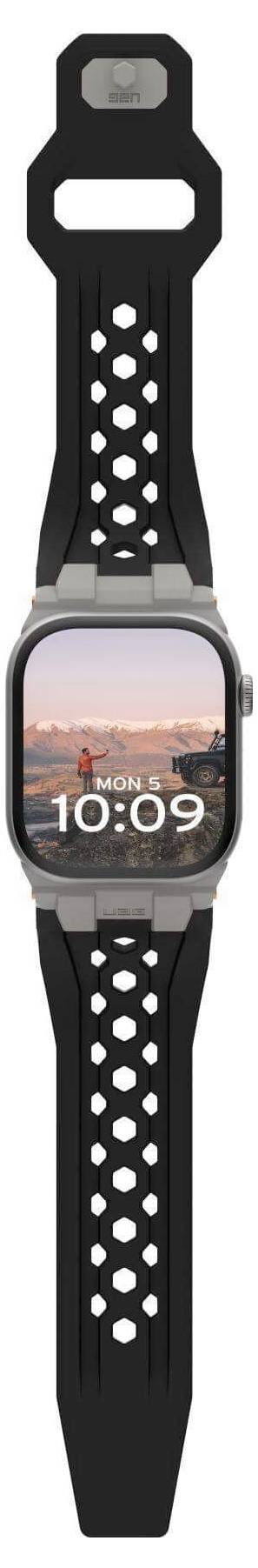 Eine Smartwatch mit schwarzem, perforiertem Armband zeigt 10:09 Uhr an. Das Display zeigt ein Landschaftsfoto mit Sonnenaufgang.