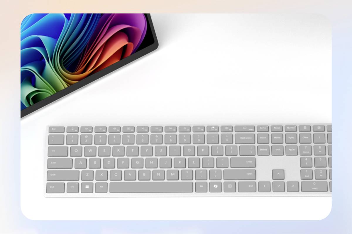 Tablet mit bunter Bildschirmgrafik oben links, daneben eine weiße Tastatur auf weißem Hintergrund.