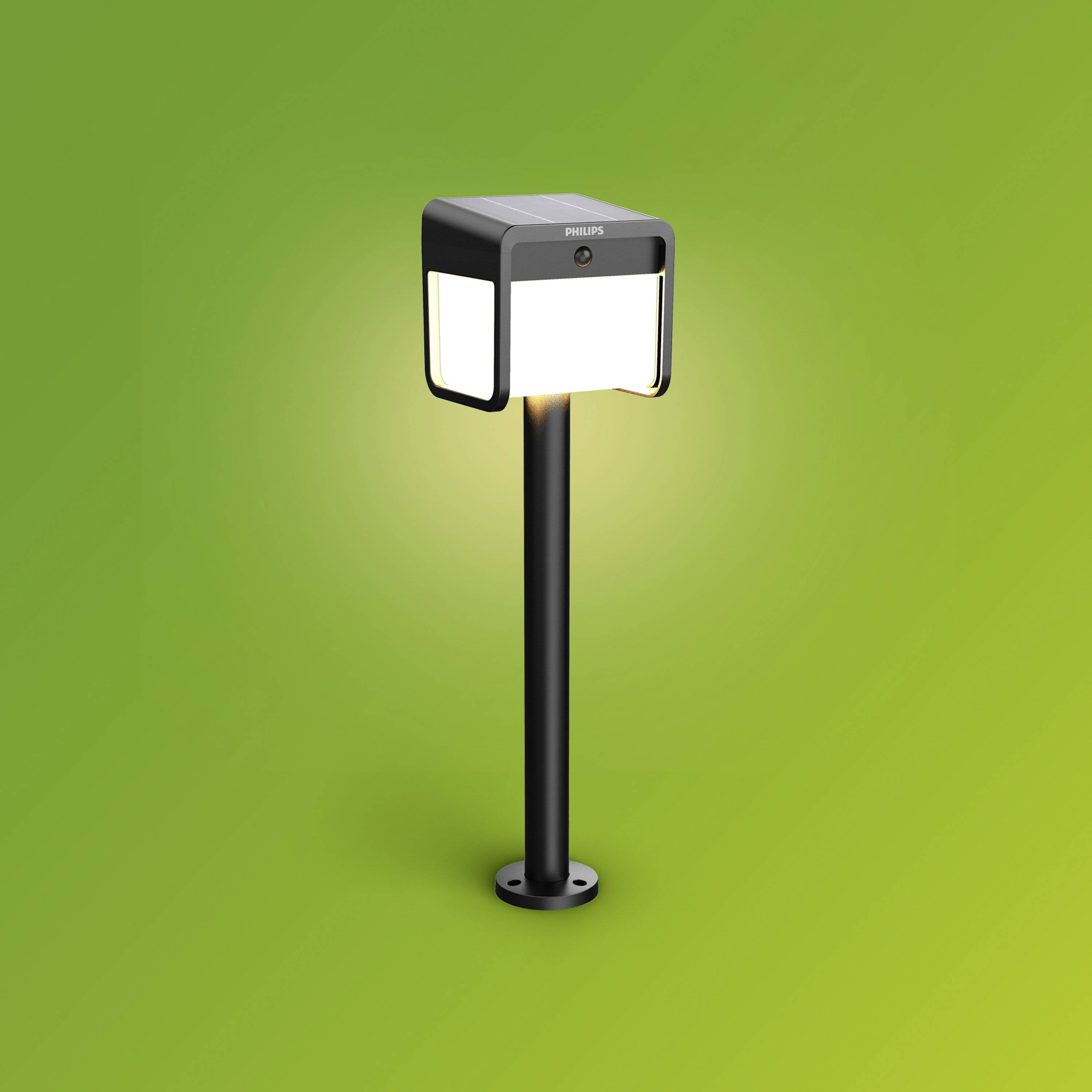 Eine moderne, rechteckige Außenleuchte von Philips auf einem grünen Hintergrund. Sie leuchtet hell, was auf ihre Funktion als Beleuchtung hinweist.
