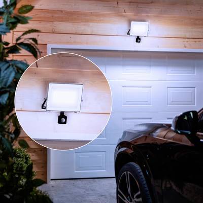 Außenleuchte beleuchtet automatisch eine Garage bei Einbruch der Dunkelheit; Auto vor der Garage geparkt.
