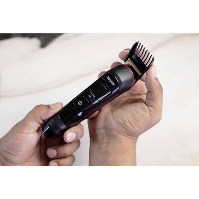 Eine Person hält einen elektrischen Haartrimmer mit schwarzem Gehäuse in der Hand. Der Trimmer hat ein verstellbares Kammaufsatz.