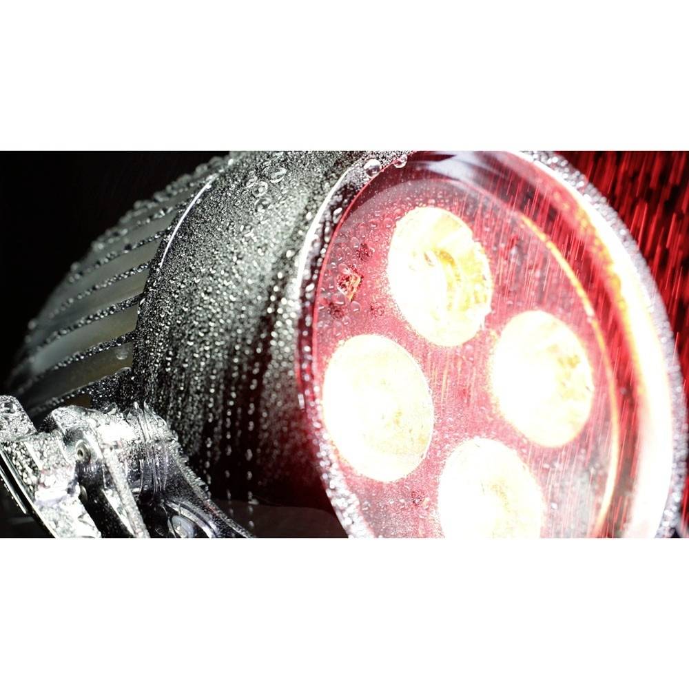 Rote LED-Lampe mit vier kreisförmigen Leuchtfeldern, von Wassertropfen bedeckt, beleuchtet den Hintergrund mit roten Lichtstrahlen.