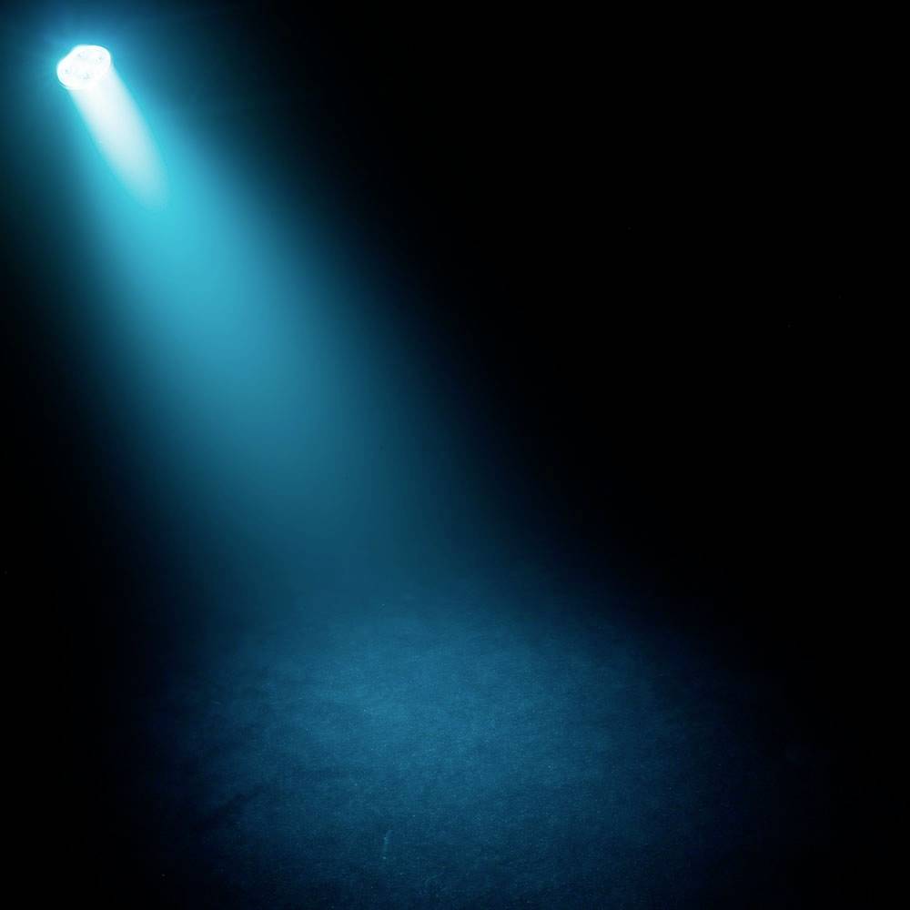 Ein blauer Lichtstrahl leuchtet von oben nach unten auf eine dunkle Fläche, erzeugt eine stimmungsvolle und fokussierte Atmosphäre.