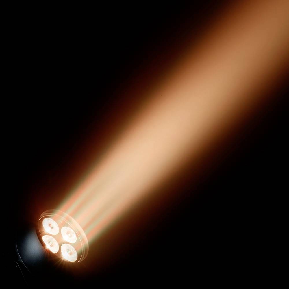 Ein orangefarbener Lichtstrahl aus einem Scheinwerfer leuchtet schräg nach oben in einem dunklen Hintergrund.