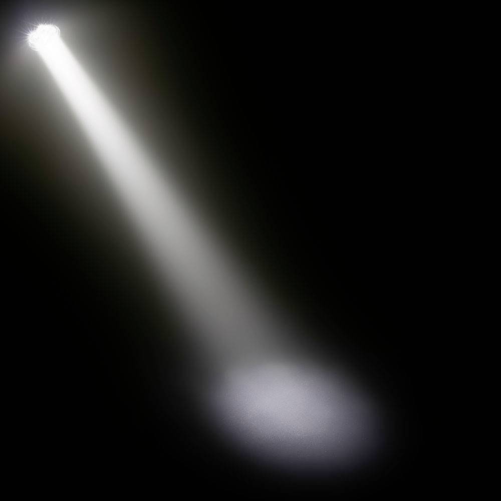 'Ein heller Lichtstrahl fällt auf eine dunkle Bühne und erzeugt einen dramatischen Effekt.'