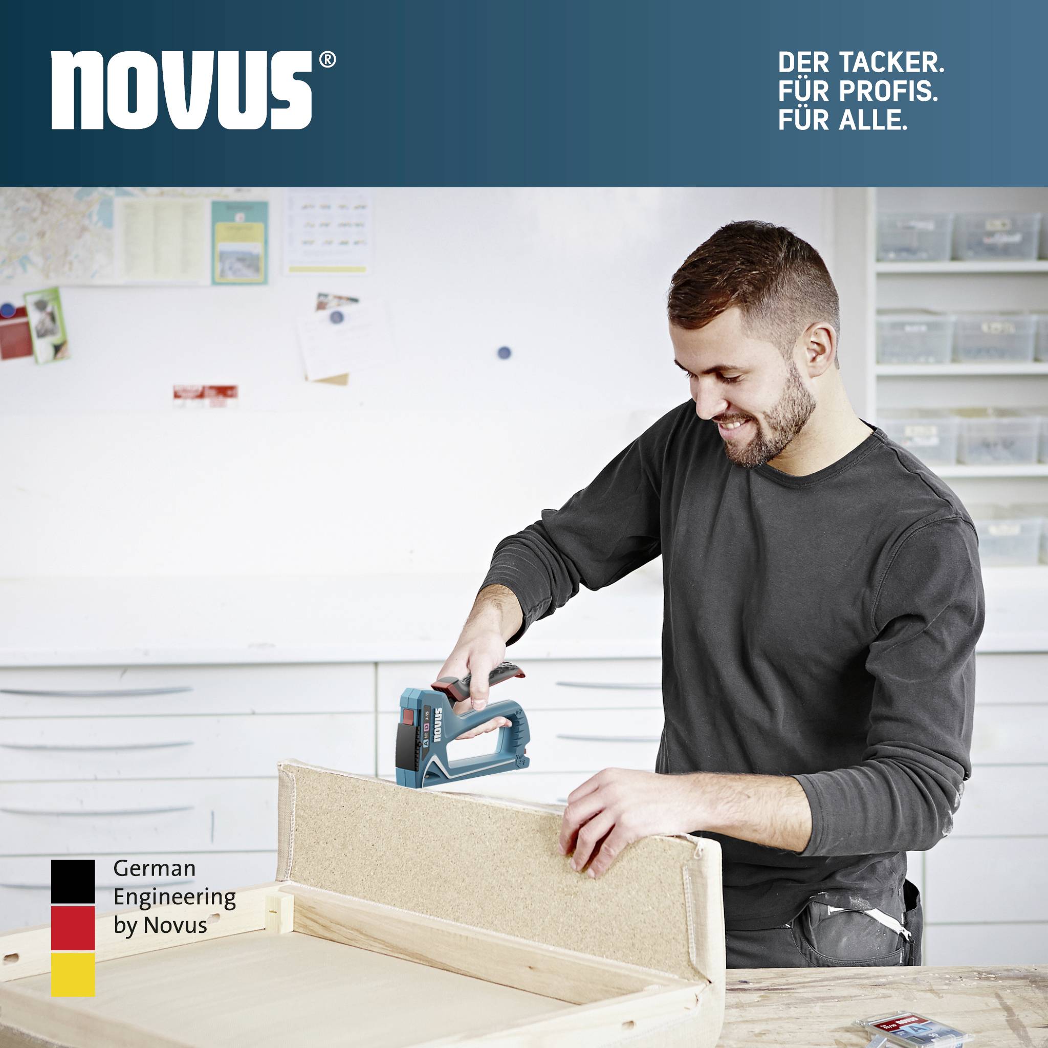 Ein Mann tackert ein Holzbrett in einer Werkstatt. Oben links das Logo 'novus' mit dem Slogan 'Der Tacker. Für Profis. Für alle.'