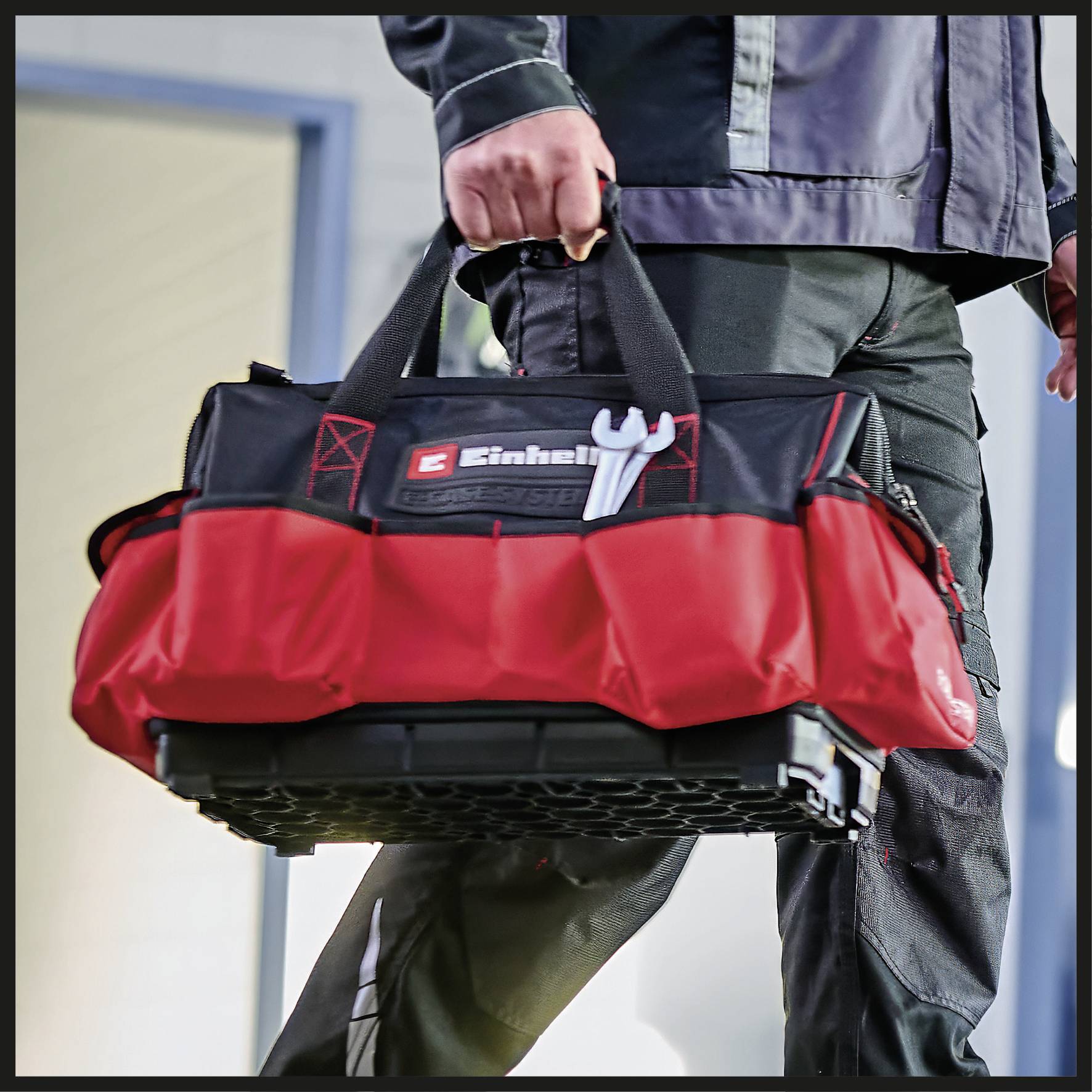 Eine Person trägt eine rote Werkzeugtasche mit dem Markennamen 'Einhell' und einem Schraubenschlüssel-Symbol darauf.