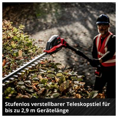Mann mit Schutzhelm und Warnweste schneidet mit einer Heckenschere eine Hecke; eingeblendeter Text: 'Stufenlos verstellbarer Teleskopstiel für bis zu 2,9 m Geräتلänge'.