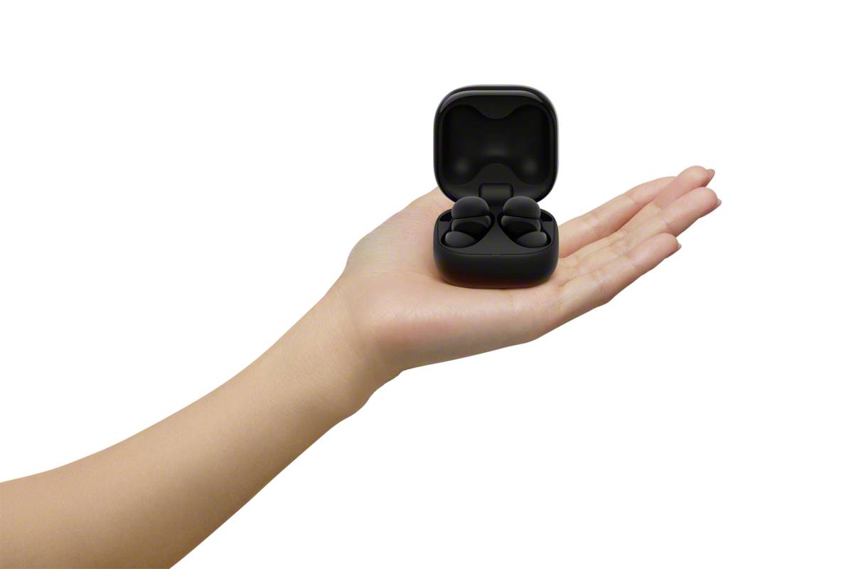 Eine Hand hält ein offenes Etui mit zwei schwarzen kabellosen Ohrhörern.