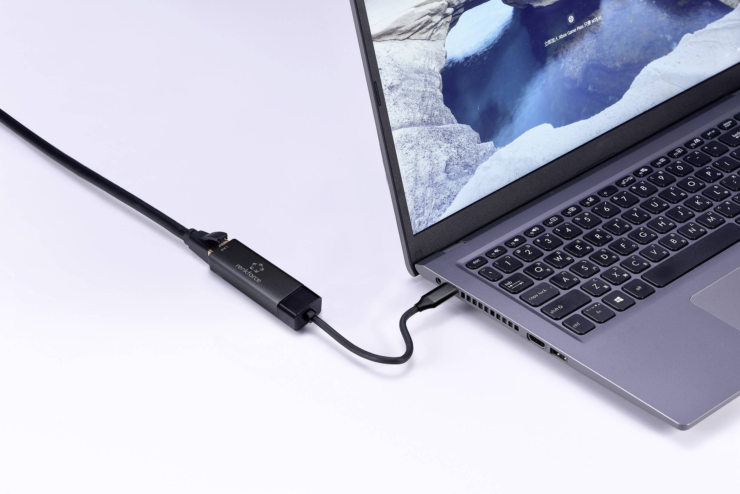 Ein Smartphone ist über ein Kabel mit einem Laptop verbunden. Der Laptop zeigt einen Bildschirmhintergrund mit einer Landschaftsszene.