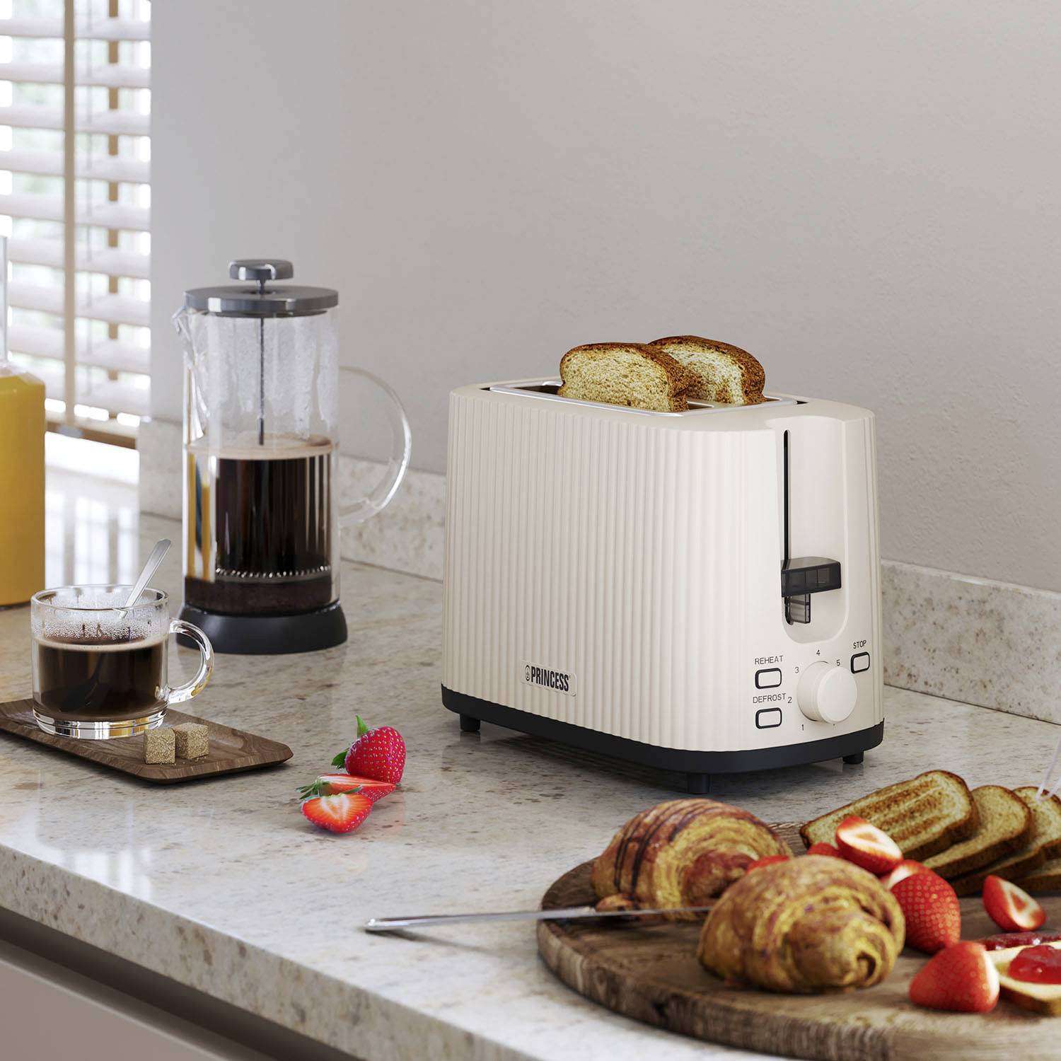 Ein Toaster mit gebräuntem Toast, neben einer Tasse Kaffee, einer Kanne, Brötchen und Erdbeeren auf einer Küchenarbeitsplatte.