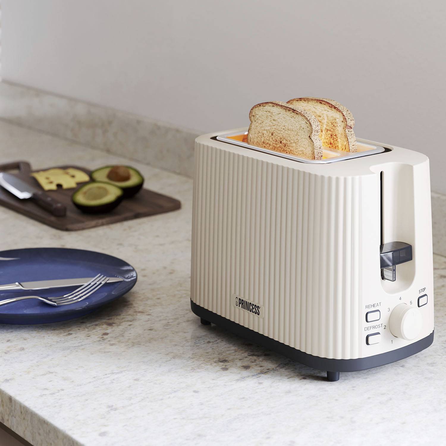 Ein heller Toaster auf einer Küchenarbeitsplatte röstet zwei Scheiben Brot. Daneben liegt ein Brett mit geschnittenen Avocados.