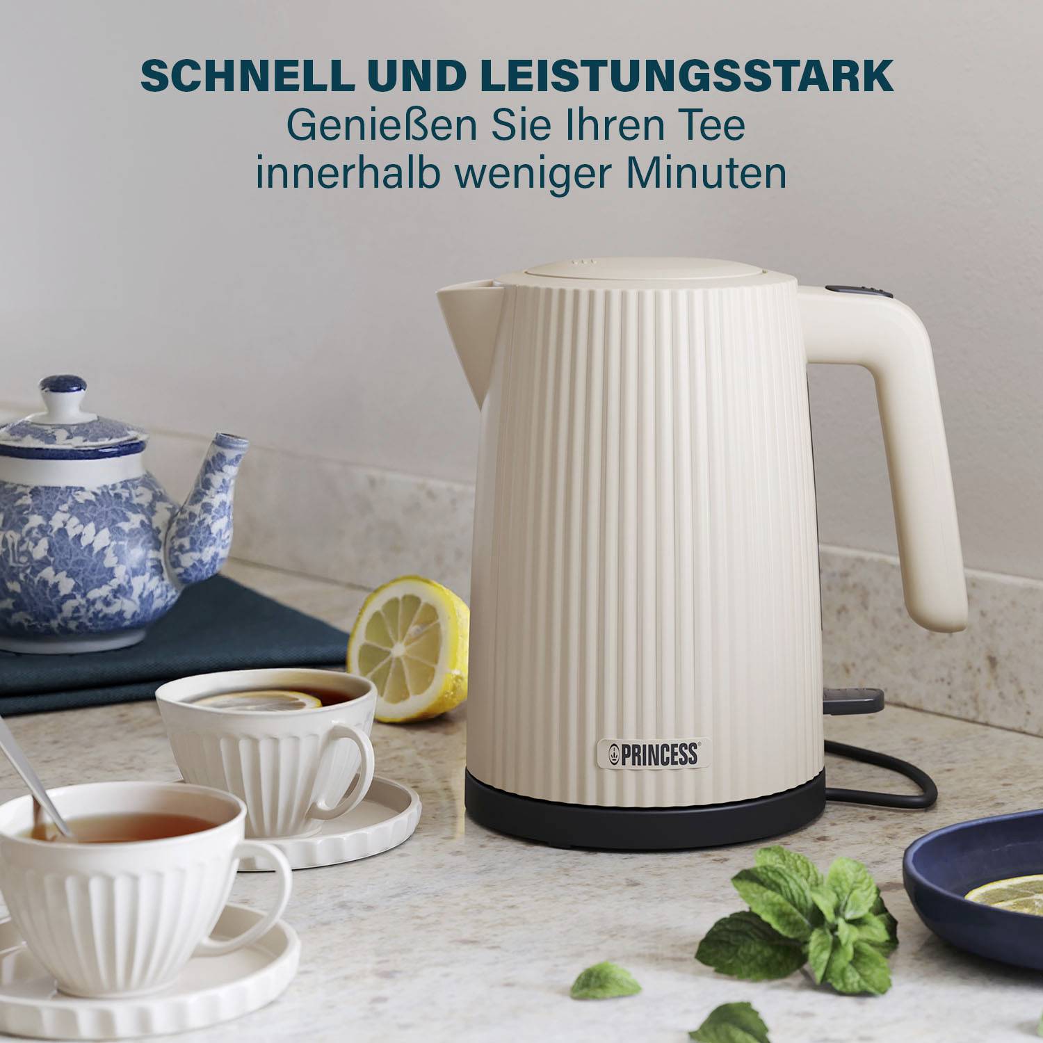 Ein Wasserkocher auf einer Küchenarbeitsplatte neben zwei Tassen Tee, einer Zitronenscheibe und einem Löffel. Text: 'Schnell und leistungsstark'.
