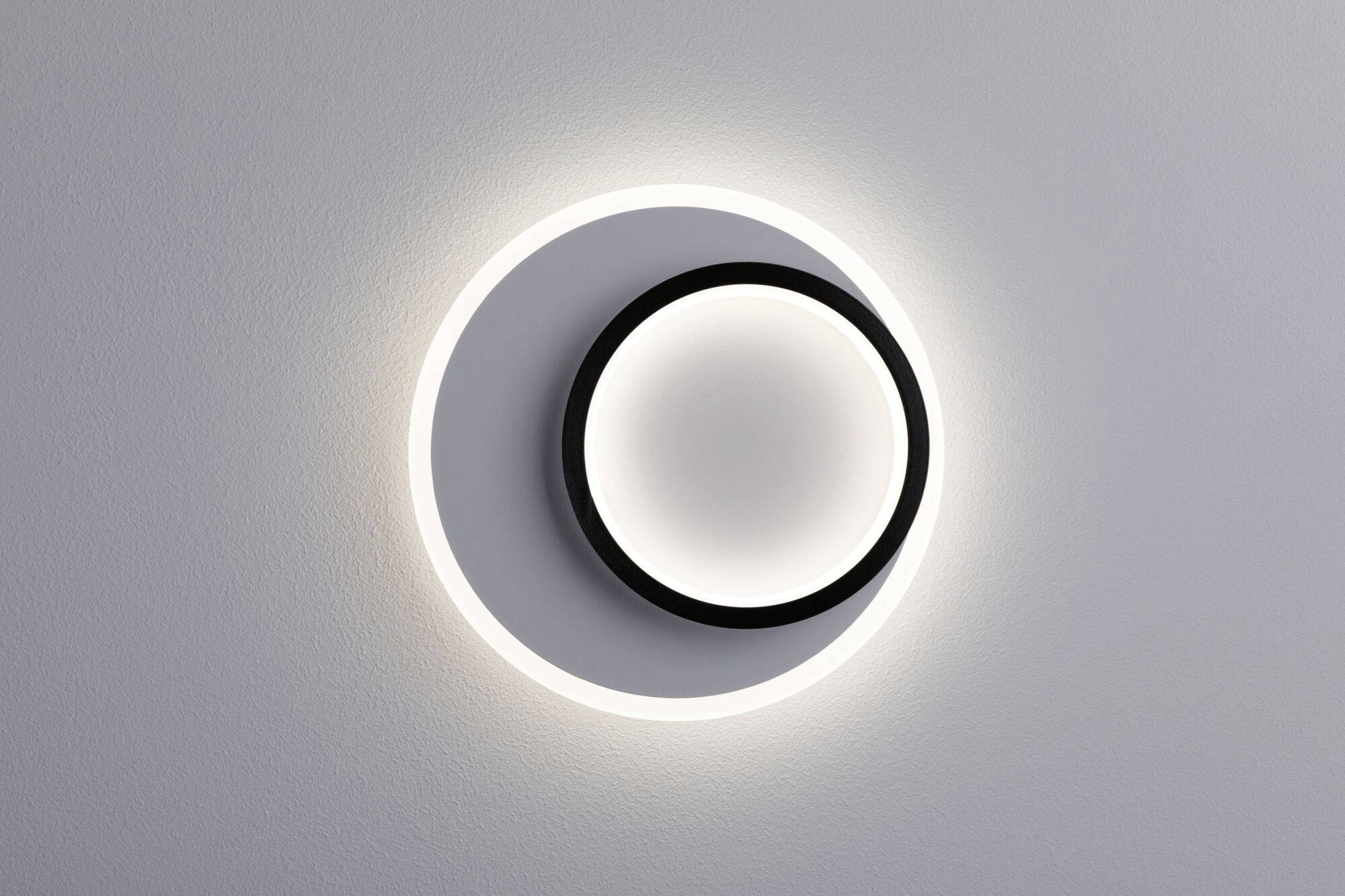 Eine moderne Wandlampe mit kreisförmigem Design, die sanftes, rundes Licht abgibt. Ideal für stilvolle Beleuchtung in Innenräumen.