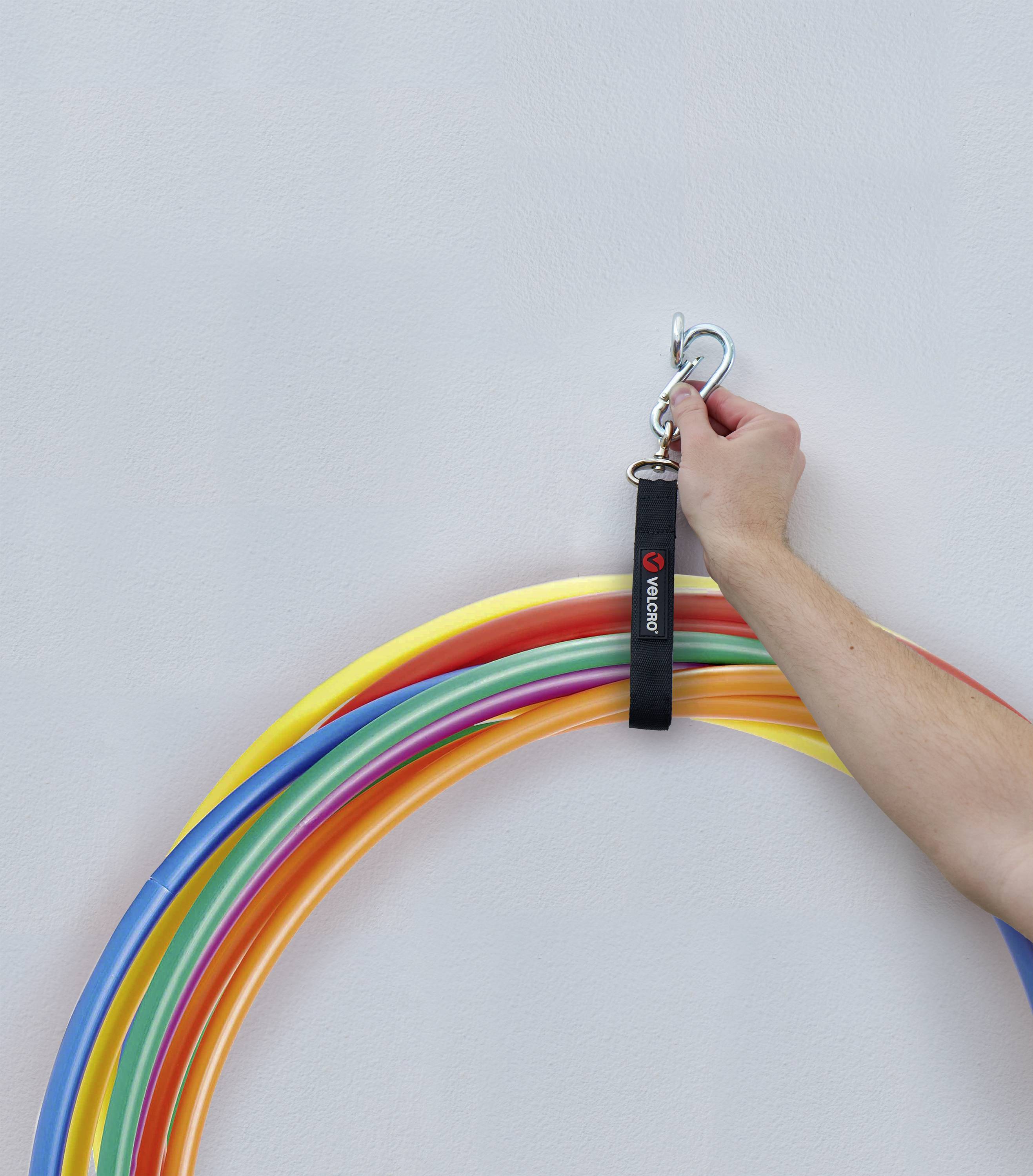 Eine Hand, die viele bunte Hula-Hoops an einem Haken an der Wand befestigt.