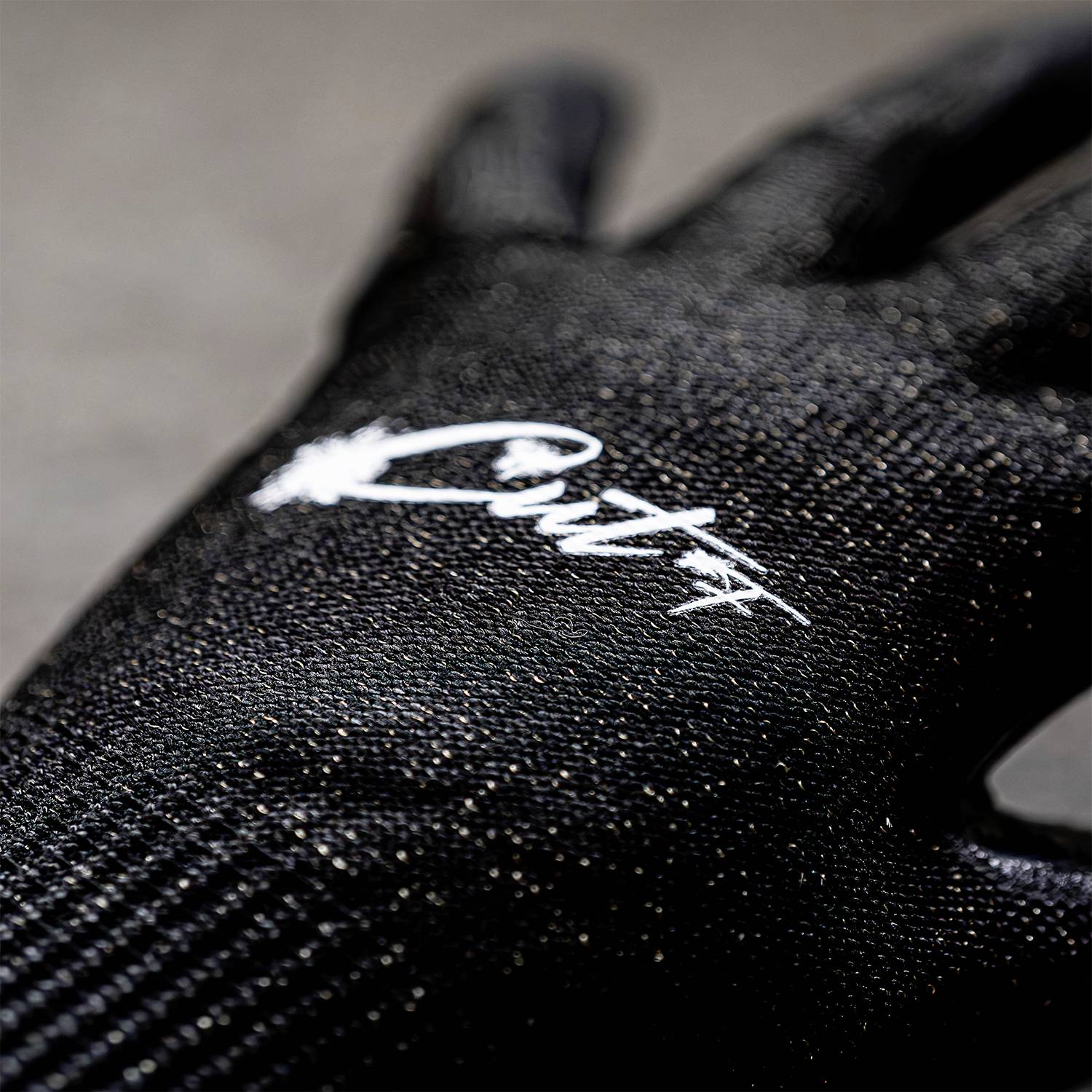 Schwarzer Handschuh mit weißem Logo-Aufdruck auf der Oberfläche, Nahaufnahme. 