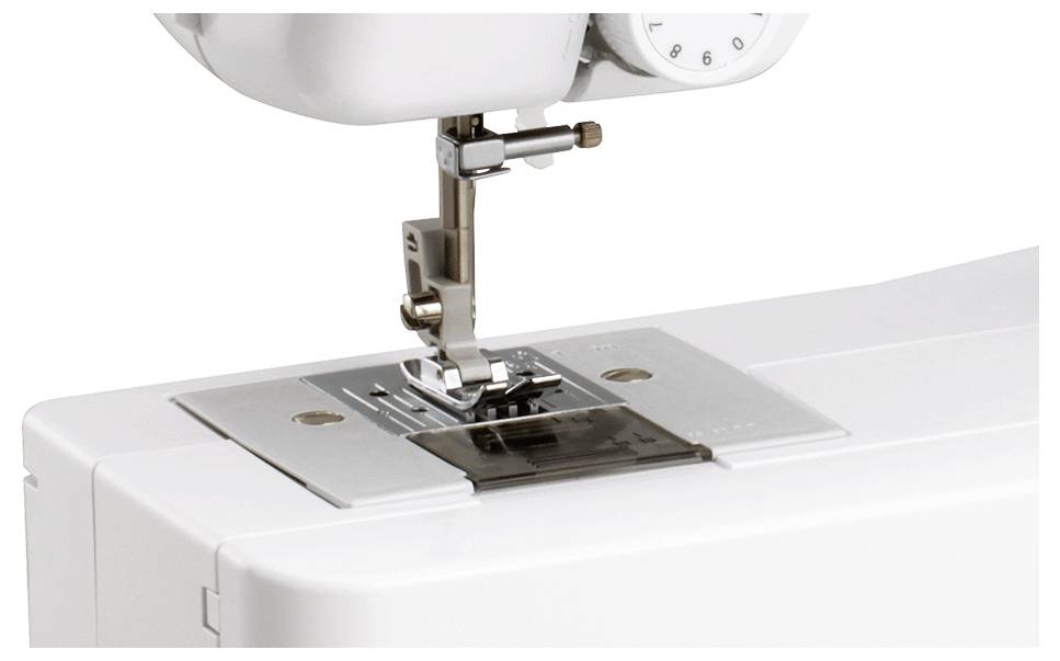 Nahaufnahme einer Nähmaschine, die den Nähfuß, die Nadel und den Transporteur zeigt.