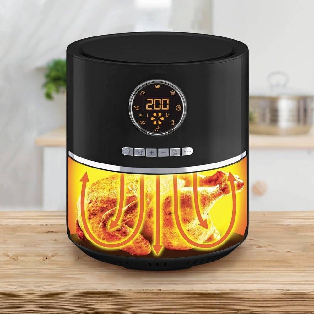 Schwarzer Airfryer auf Holztisch, zeigt goldbraunes Hähnchen innen. Display zeigt 200 Grad. Küche im Hintergrund.