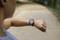 Eine Person schaut auf eine Smartwatch beim Laufen auf einem Weg im Freien. Die Uhr zeigt Fitnessdaten an.