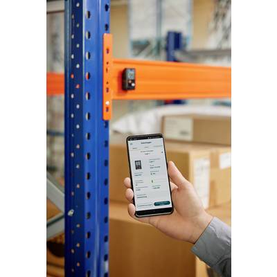 Eine Hand hält ein Smartphone vor einem Lagerregal. Auf dem Bildschirm sind Lagerverwaltungsdetails zu sehen. Im Hintergrund sind Kartons gestapelt.